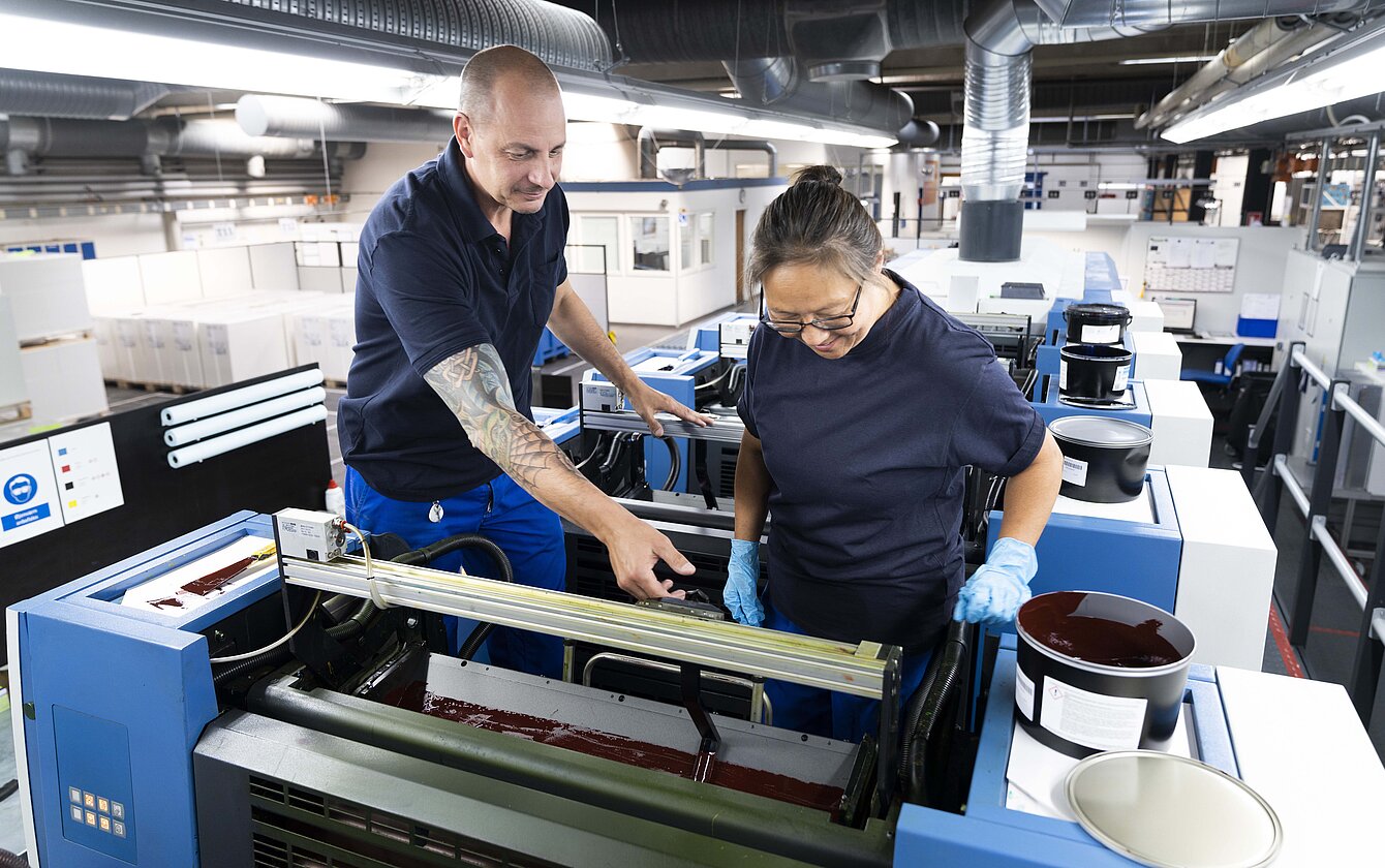 Mitarbeiter arbeiten gemeinsam an Druckmaschine