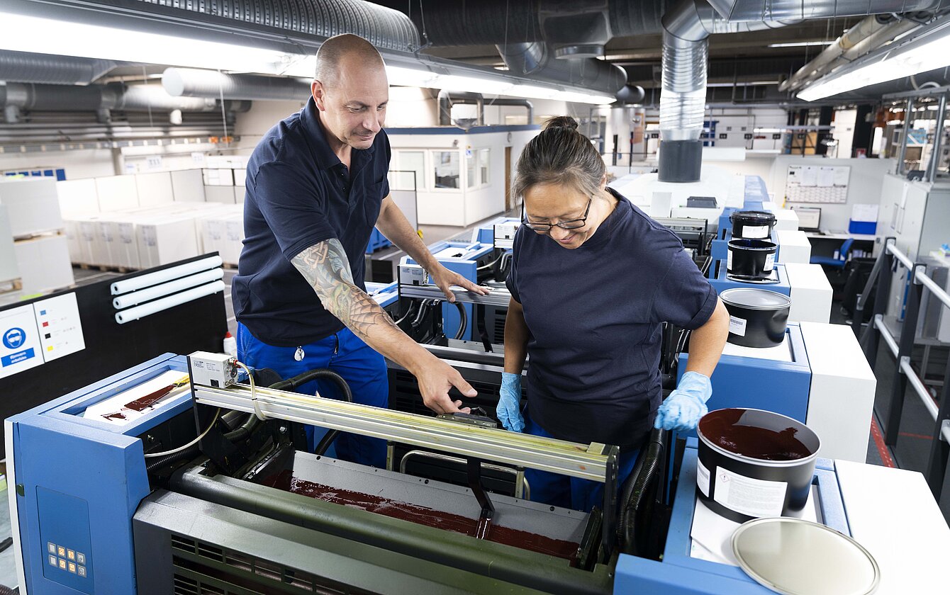 Mitarbeiter arbeiten gemeinsam an Druckmaschine