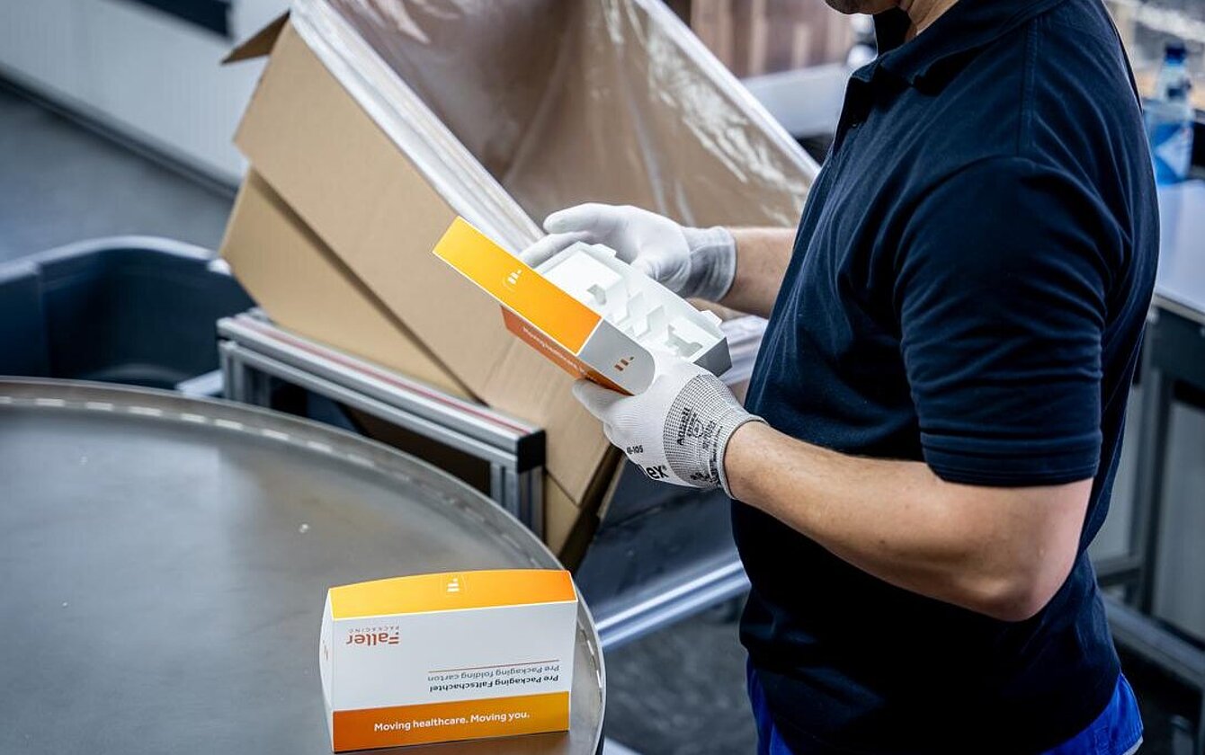 Qualitätskontrolle beim PrePackaging Service von Faller Packaging – Mitarbeiter prüft vorkonfektionierte Faltschachteln.