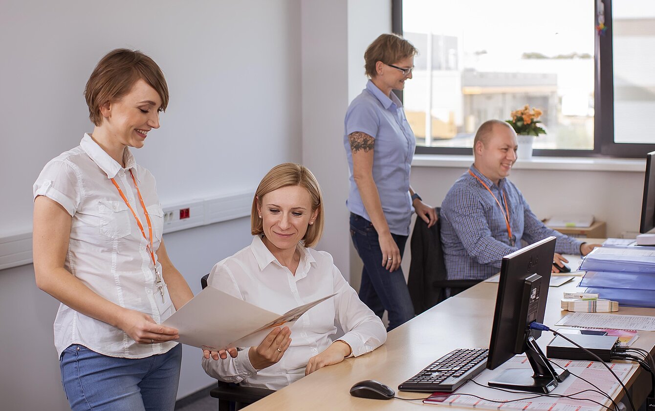 Büroszene am Standort Łódź – Mitarbeitende von Faller Packaging besprechen Unterlagen und arbeiten am Computer.