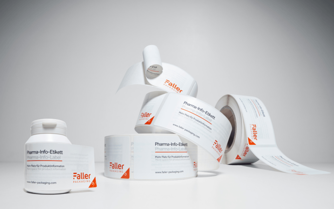 Rollen von Haftetiketten für pharmazeutische Informationen, die auf einem neutralen Hintergrund angeordnet sind. Die Etiketten sind klar beschriftet und zeigen die Marke Faller.