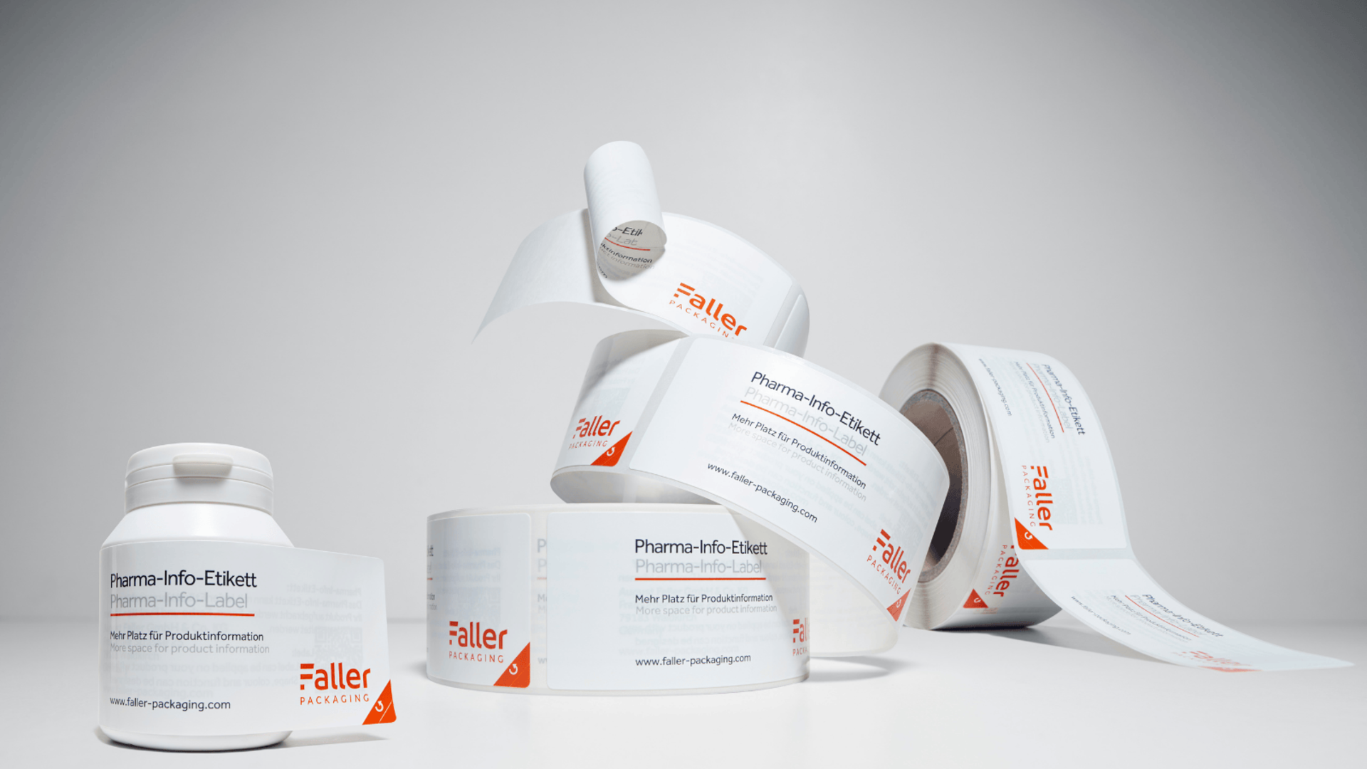 Rollen von Haftetiketten für pharmazeutische Informationen, die auf einem neutralen Hintergrund angeordnet sind. Die Etiketten sind klar beschriftet und zeigen die Marke Faller.
