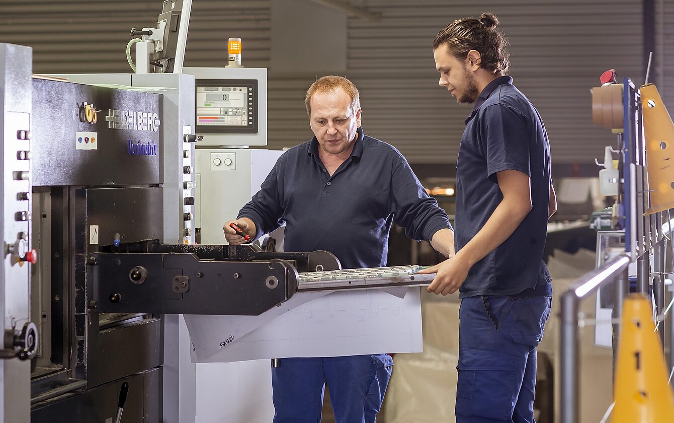 Mitarbeitende im Werk Łódź bei der Arbeit an einer Produktionsmaschine zur Herstellung von Faltschachteln.